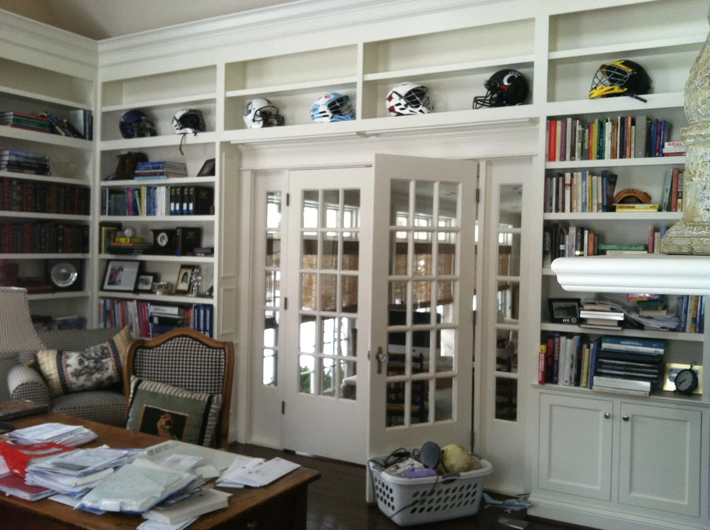 Floor-to-ceiling white home library with built-in shelving framing French doors