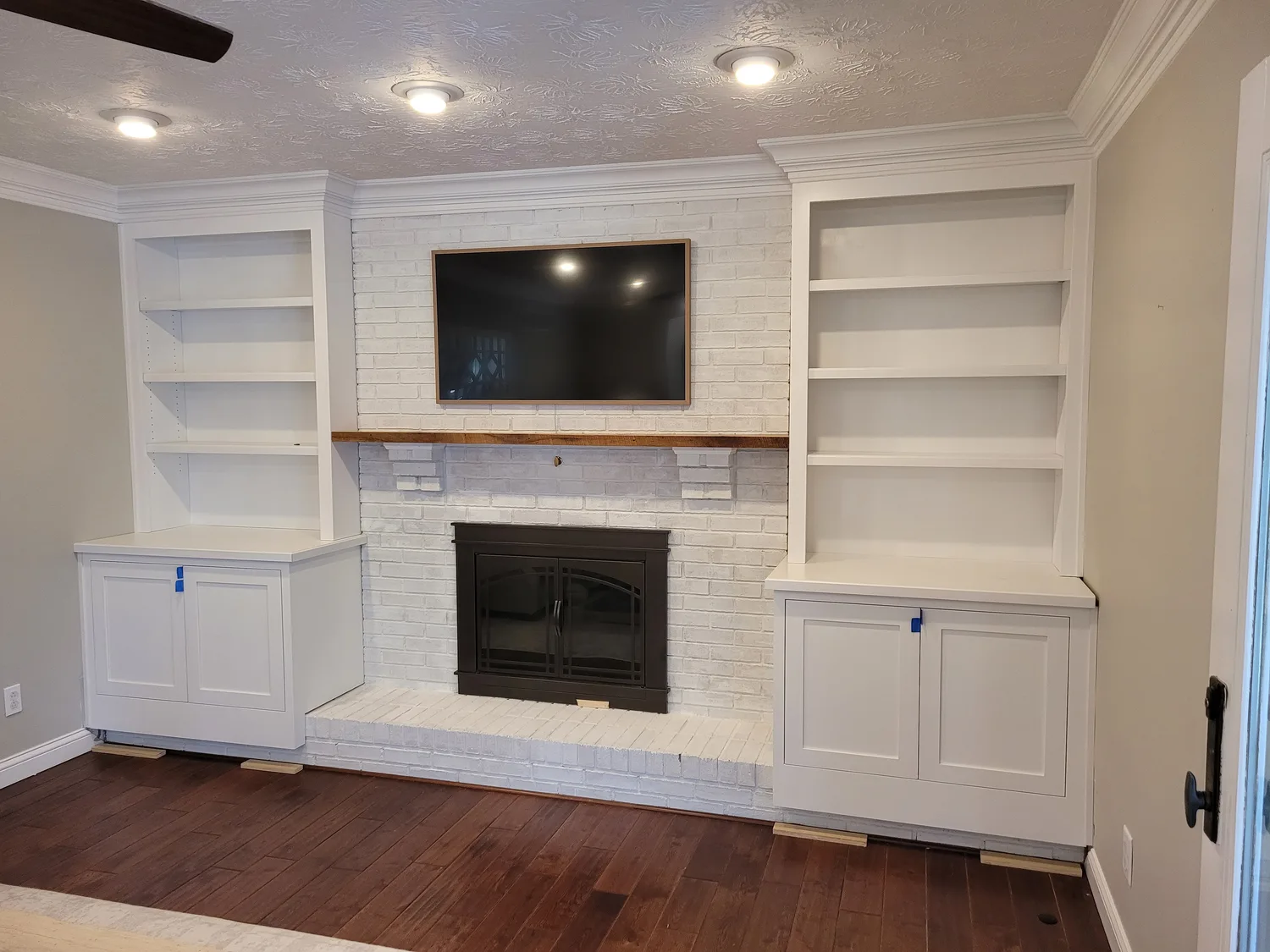 White built-in shelving flanking a painted brick fireplace