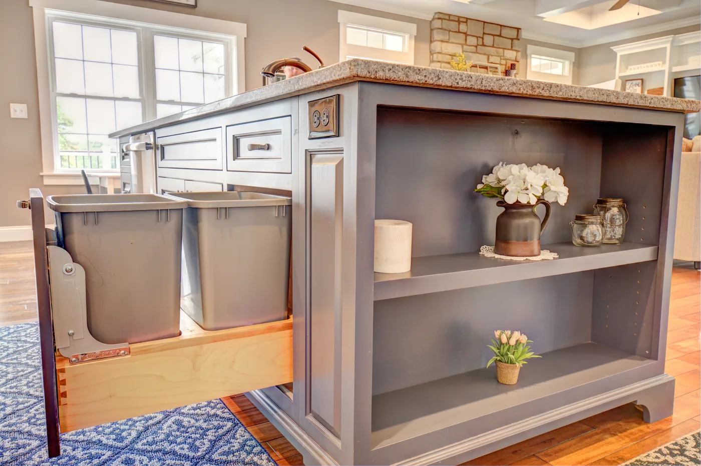 Gray island with hidden pull-out trash and open shelf