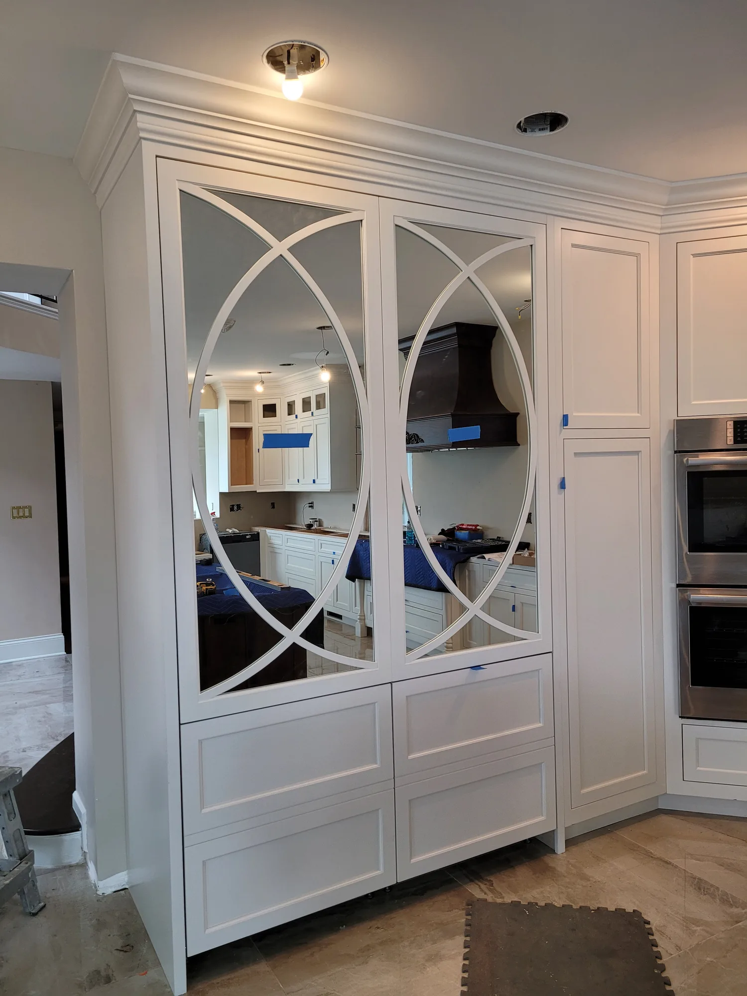 White kitchen cabinetry with oval mullion mirror doors