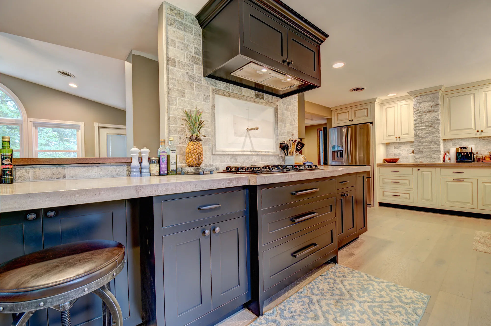 Custom navy kitchen island with stone backsplash and white perimeter cabinetry by Wildwater Custom Cabinetry