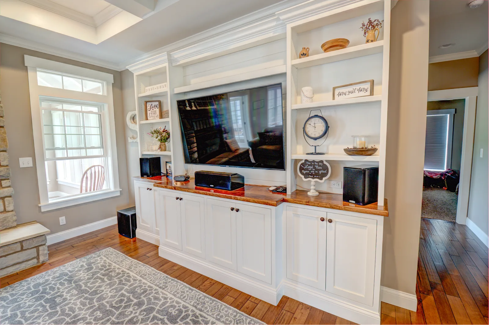 White entertainment-center built-in with wood counters under a coffered ceiling